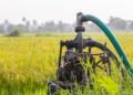 Water pump standing in a green farm field used for crop irrigation