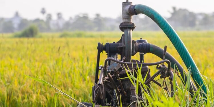 Water pump standing in a green farm field used for crop irrigation