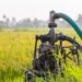 Water pump standing in a green farm field used for crop irrigation