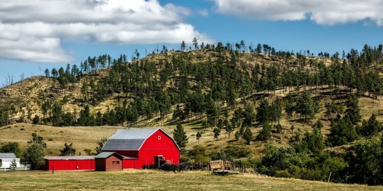 Red wooden shed standing on open farmland under the sky