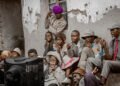 Group of people in Malawi gathered outdoors watching a television set together