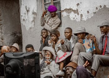 Group of people in Malawi gathered outdoors watching a television set together