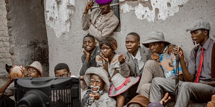 Group of people in Malawi gathered outdoors watching a television set together