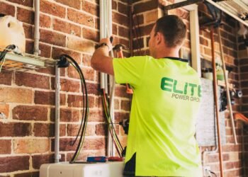 Electrician installing a home solar battery storage system on a wall