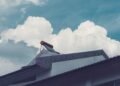 Solar water heater tank with evacuated glass tubes mounted on a building rooftop under a cloudy sky