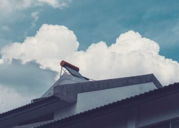 Solar water heater tank with evacuated glass tubes mounted on a building rooftop under a cloudy sky