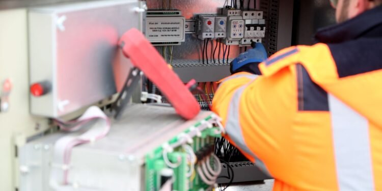 Technician checking and maintaining a wall-mounted solar inverter and its wiring